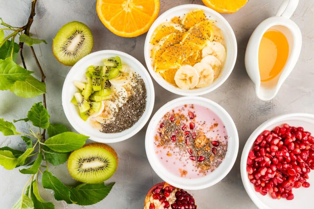Tigelas de smoothies e iogurtes com frutas frescas e sementes saudáveis.