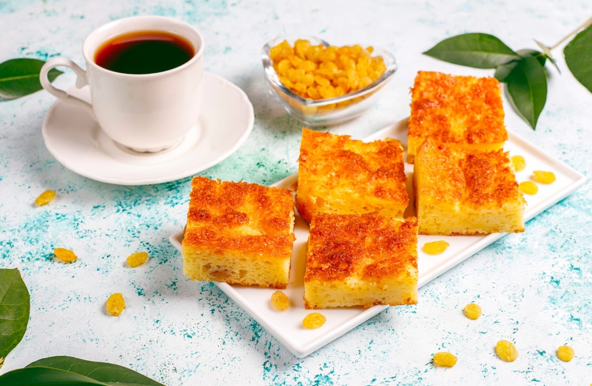 Bolo de fubá fofinho acompanhado de café e frutas, ideal para um café delicioso e prático.