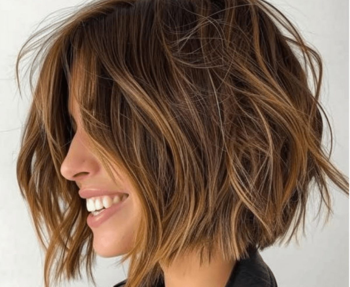 Mulher com corte bob texturizado e luzes douradas, sorrindo e destacando um estilo moderno.