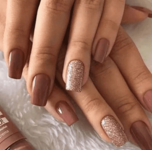 Unhas decoradas com esmalte marrom e detalhes em glitter, tendência de 2024.