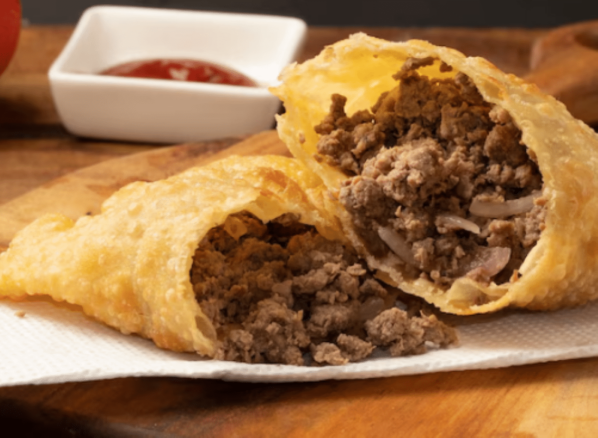 Pastel assado na Air fryer com recheio de carne moída, cortado ao meio para mostrar o interior.