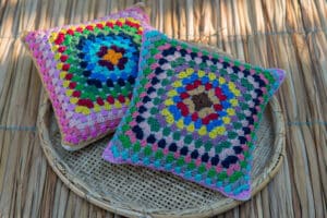 Almofadas de crochê coloridas com padrão geométrico, trazendo um toque vibrante e artesanal à decoração.