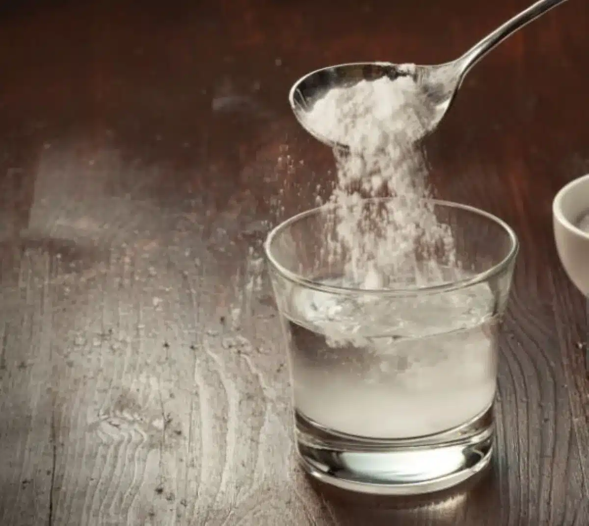 Pessoa adicionando bicarbonato de sódio em um copo com água, representando um banho de assento.