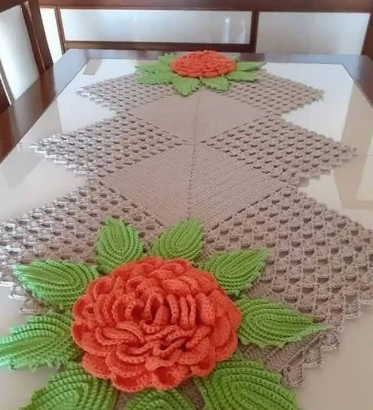 Caminho de mesa em crochê com flores e folhas em alto relevo.