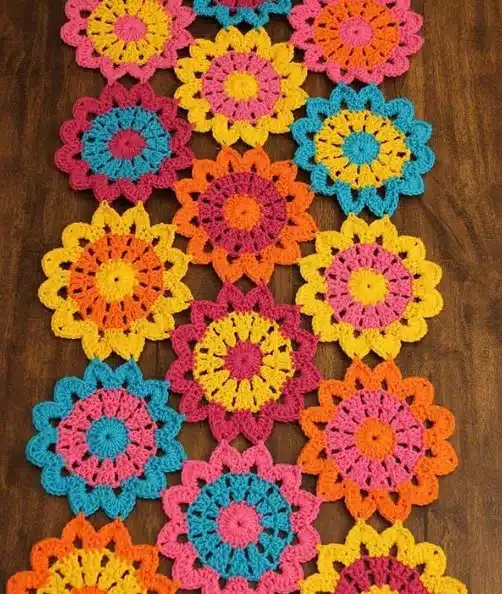 Caminho de mesa de crochê com flores coloridas, mostrando o trabalho artesanal.