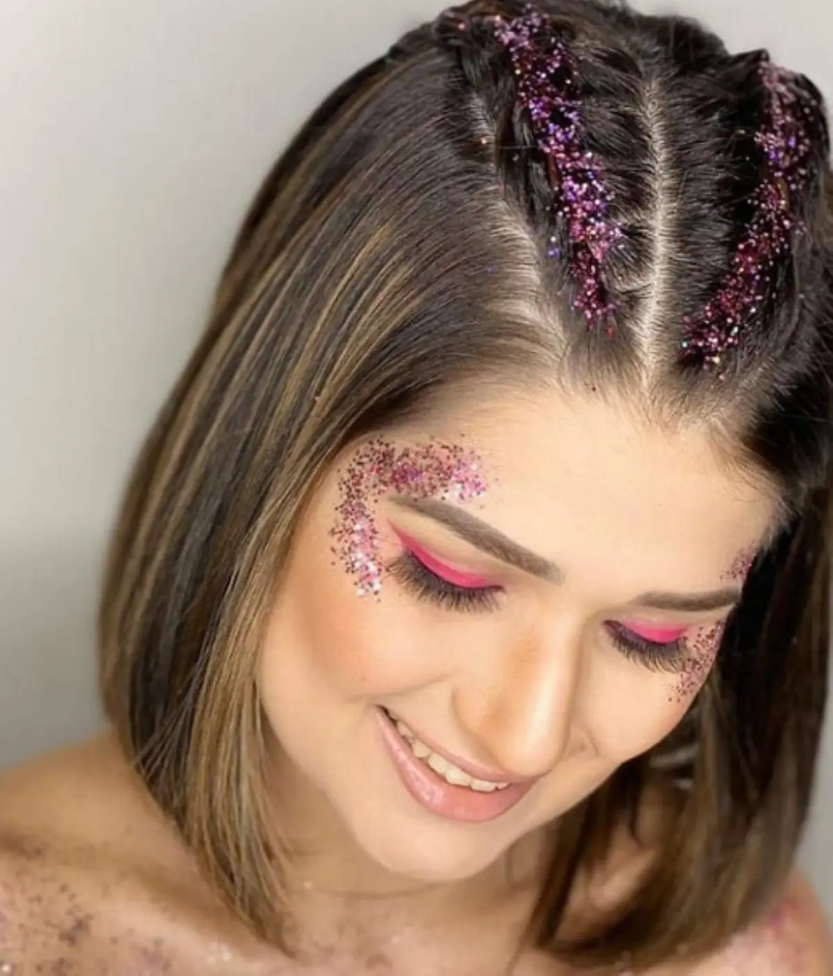Mulher com cabelo curto e estiloso, com tranças e glitter no rosto, ideal para o Carnaval.
