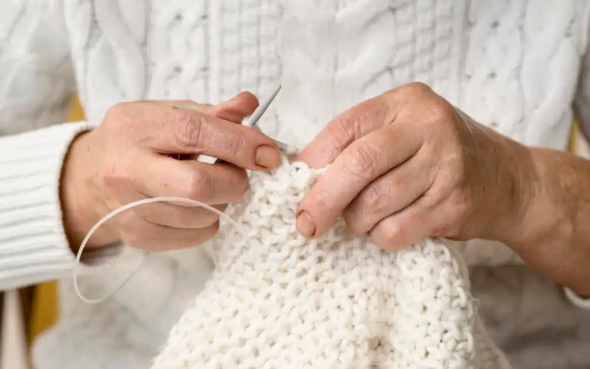 Pessoa fazendo crochê em um caminho de mesa branco.