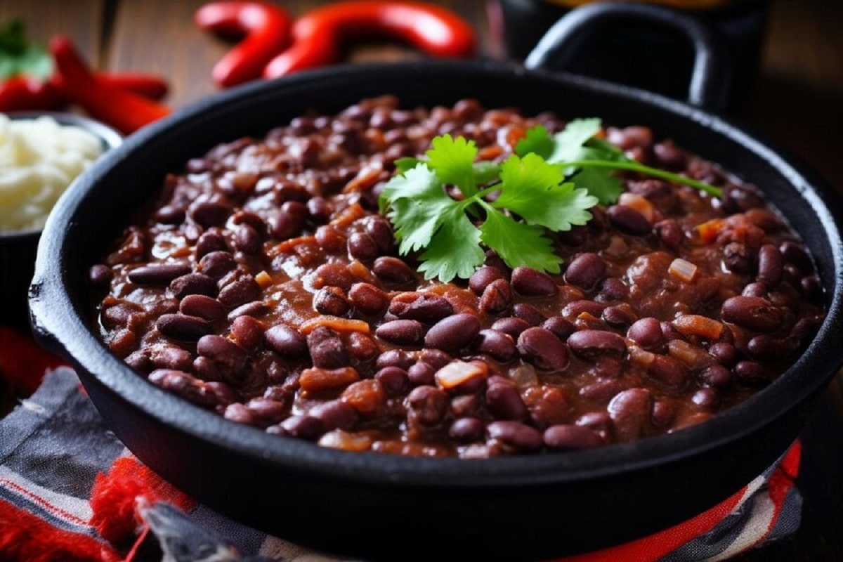 Feijão bem temperado servido em panela de ferro com temperos frescos.