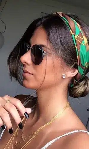 Mulher com coque baixo e lenço estampado verde, criando um visual estiloso e elegante.