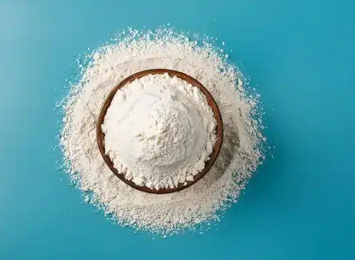 Tigela com polvilho doce sobre uma superfície azul, ingrediente essencial para a textura crocante do bolo.