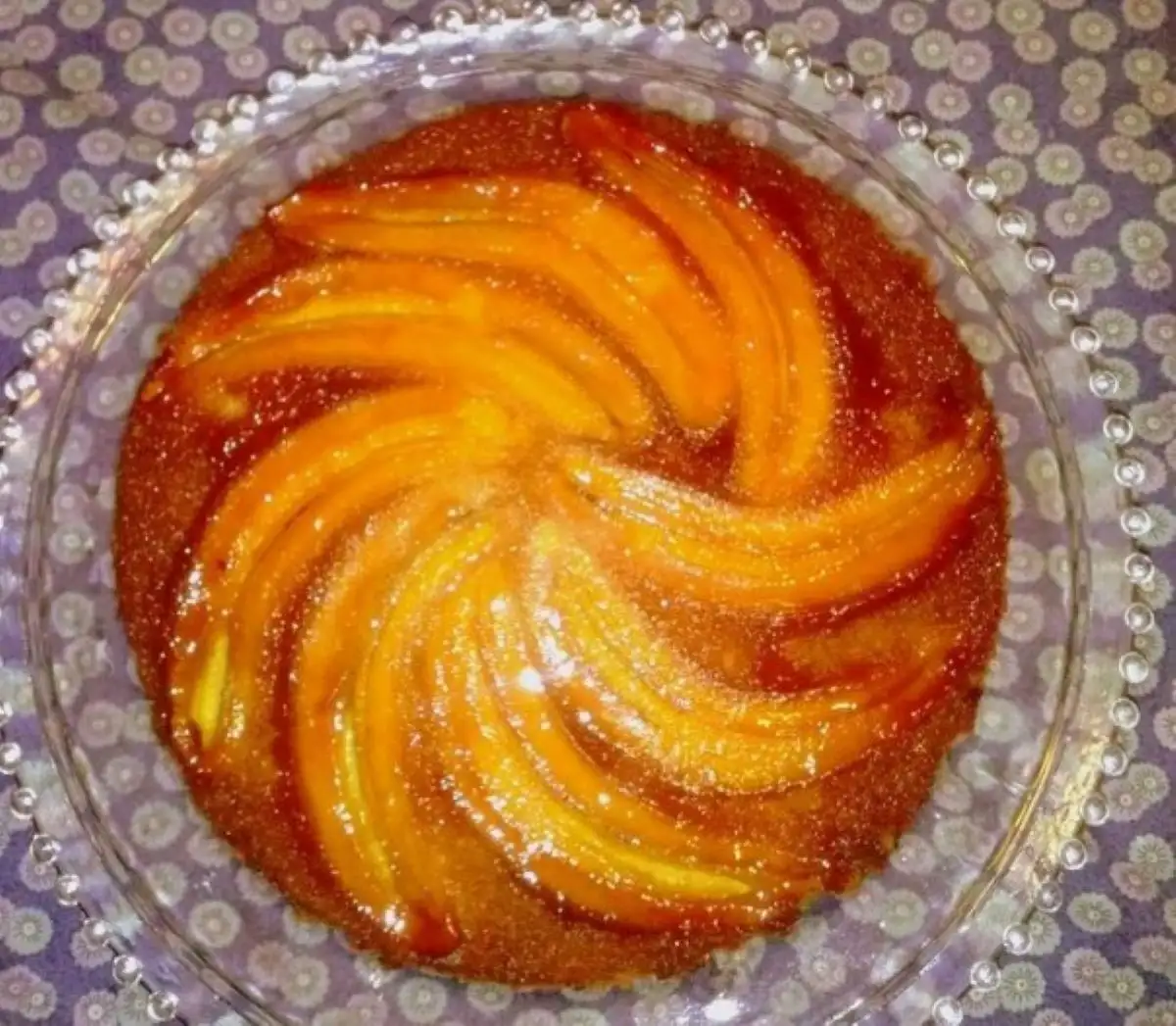 Torta de banana caramelizada servida em prato de vidro decorado.