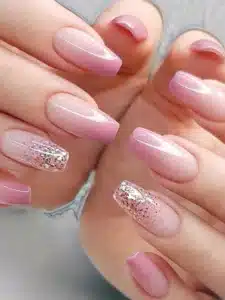 Unhas decoradas em tons de rosa com brilho, seguindo as tendências de 2025