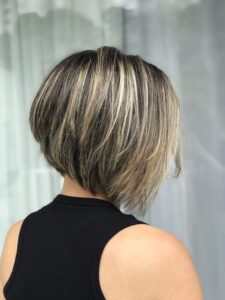 Bob desfiado assimétrico com luzes, criando um visual moderno e cheio de movimento.