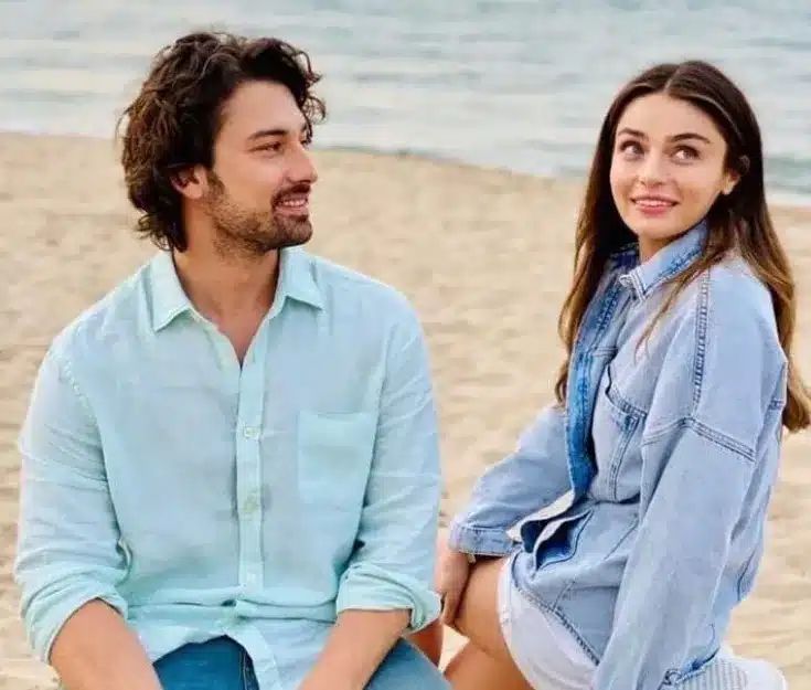 Cena romântica da novela 'Amor na Ilha', com os protagonistas sentados na praia em um momento de conexão.