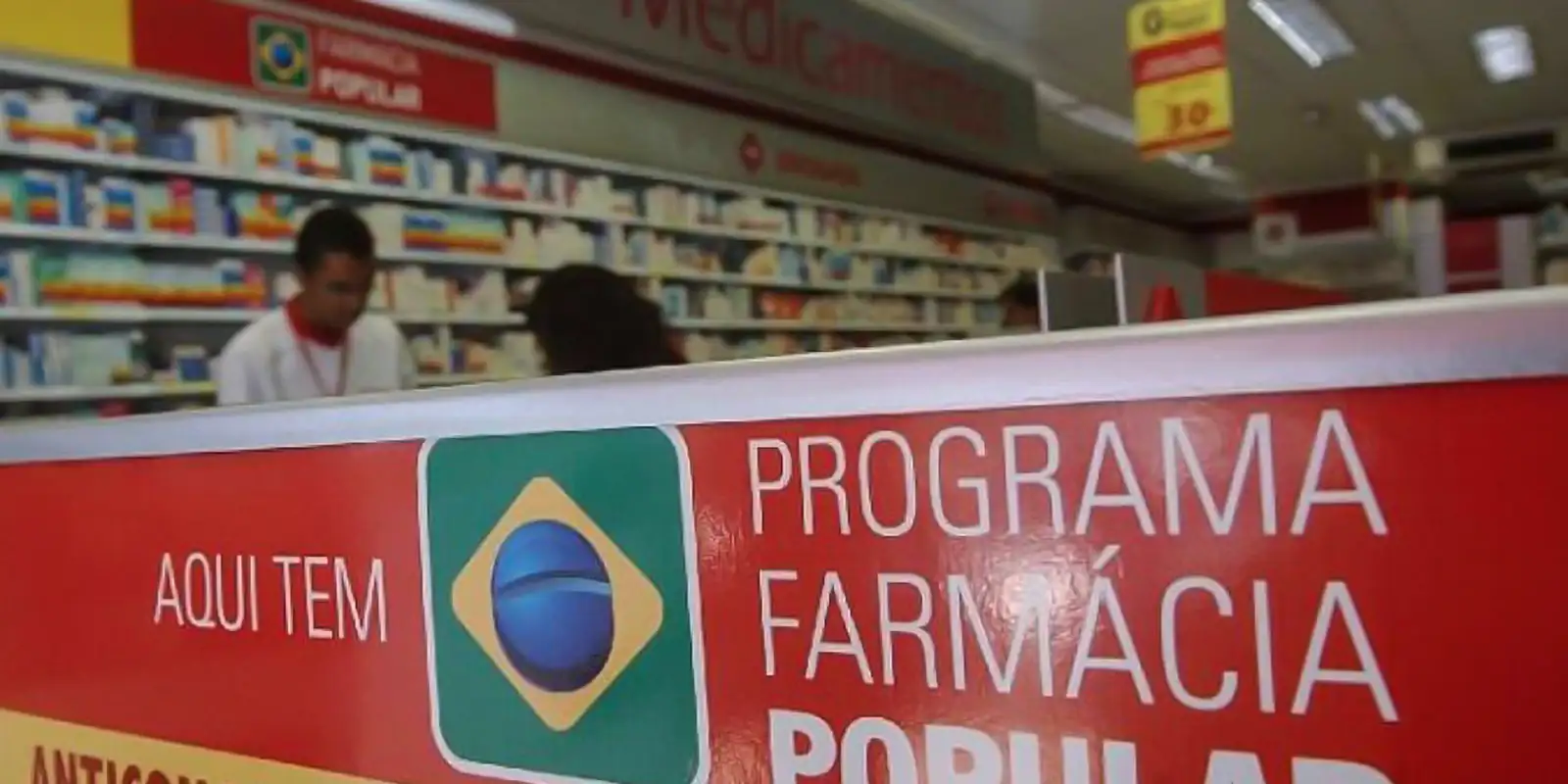 "Adesivo do programa Farmácia Popular visível em uma farmácia, destacando a identificação do local."