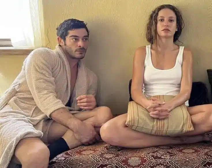 Cena da novela turca 'A Lenda de Shahmaran', com os protagonistas sentados em um ambiente íntimo e de tensão emocional.