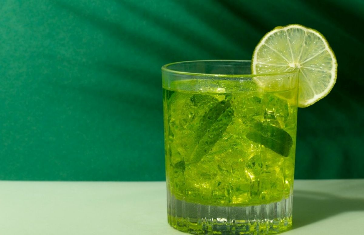 Copo de caipirinha verde com limão e folhas de hortelã, símbolo de uma caipirinha bem feita.
