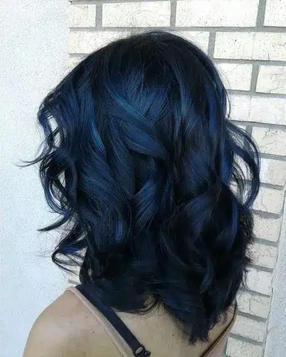 Cabelo azul profundo com ondas suaves, oferecendo um visual ousado e inovador, representando a tendência de cor para o inverno de 2025.