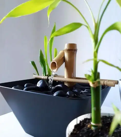 Fonte decorativa de bambu com pedras e plantas.