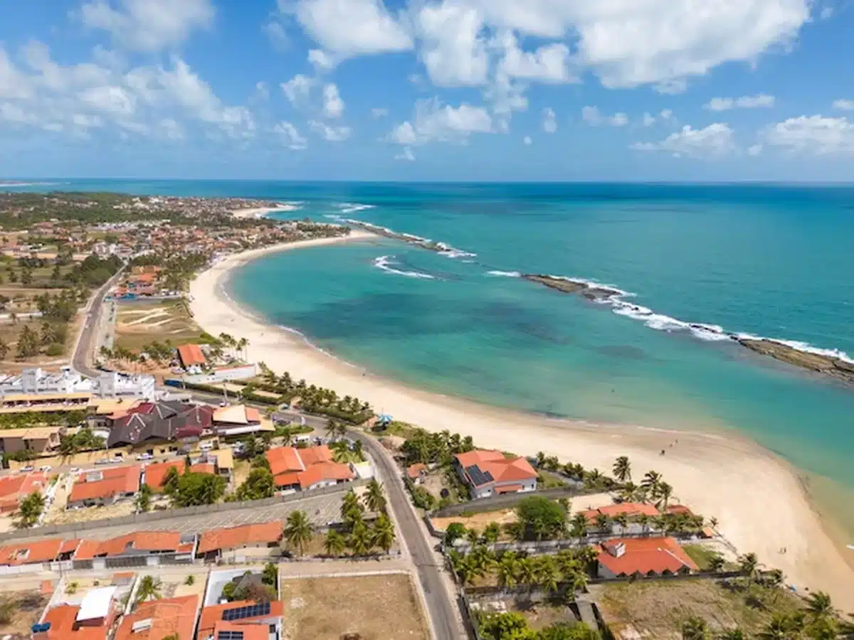 Vista aérea da praia de Barra de Tabatinga, com águas cristalinas e litoral rodeado por falésias coloridas.