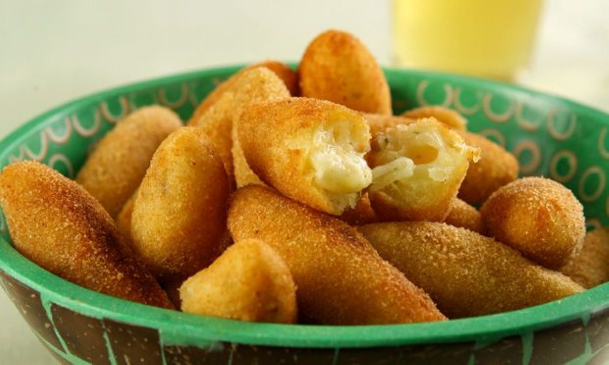 Bolinho de mandioca crocante recheado com queijo, servido em uma tigela.