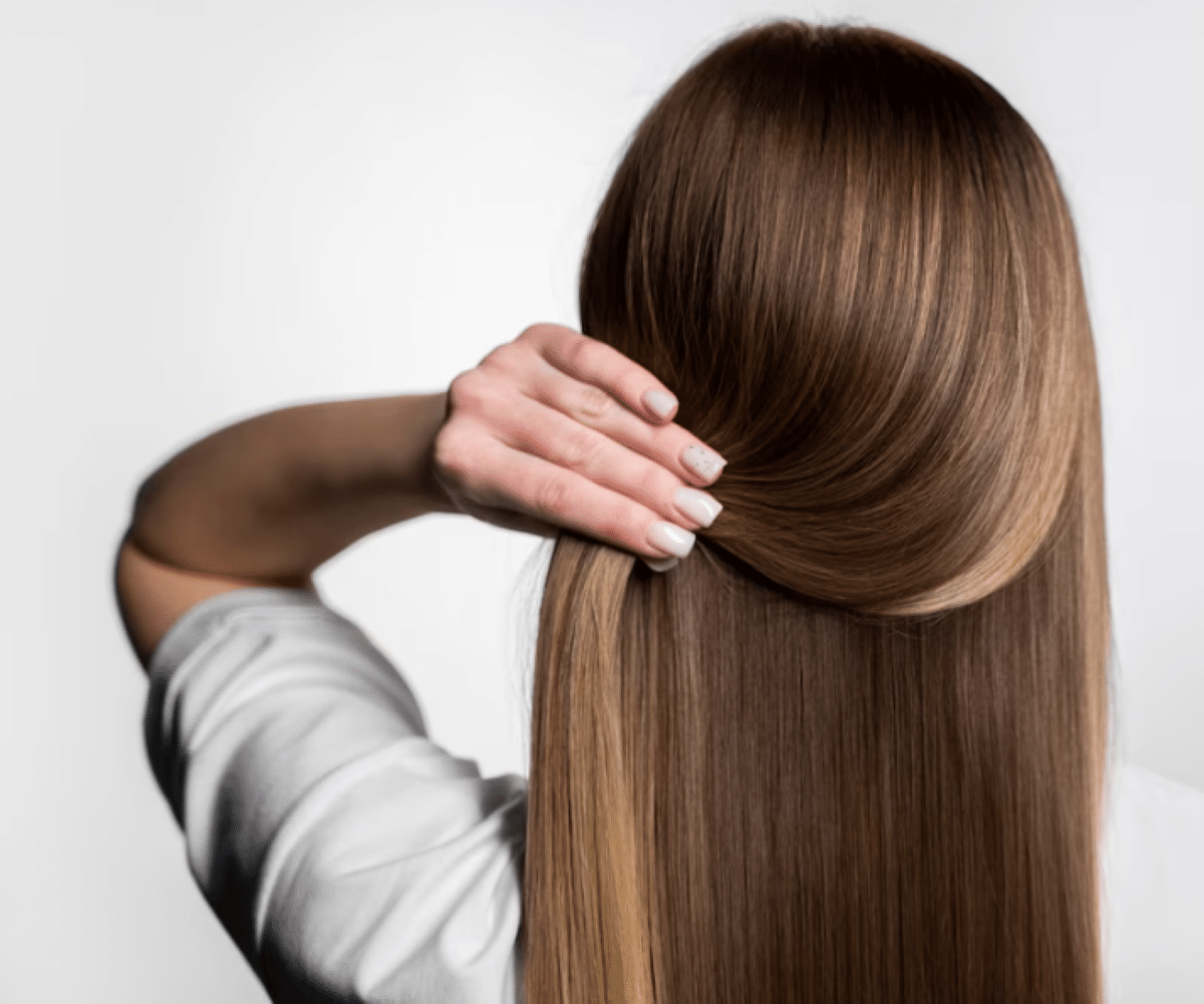 Mulher arrumando o cabelo, com uma das mãos segurando uma mecha de cabelo.