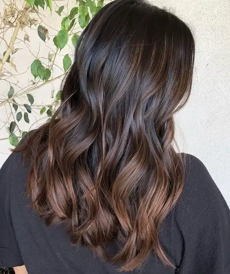 Cabelo castanho escuro em ondas suaves, com brilho natural e profundidade, representando a tonalidade café expresso, uma opção sofisticada para o inverno.