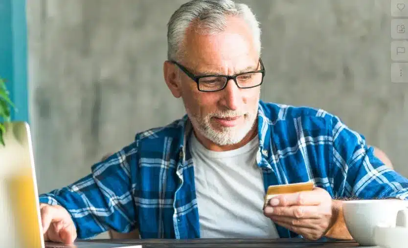 Idoso segurando um cartão de crédito, representando os descontos adicionais oferecidos por algumas instituições financeiras além da meia-entrada.