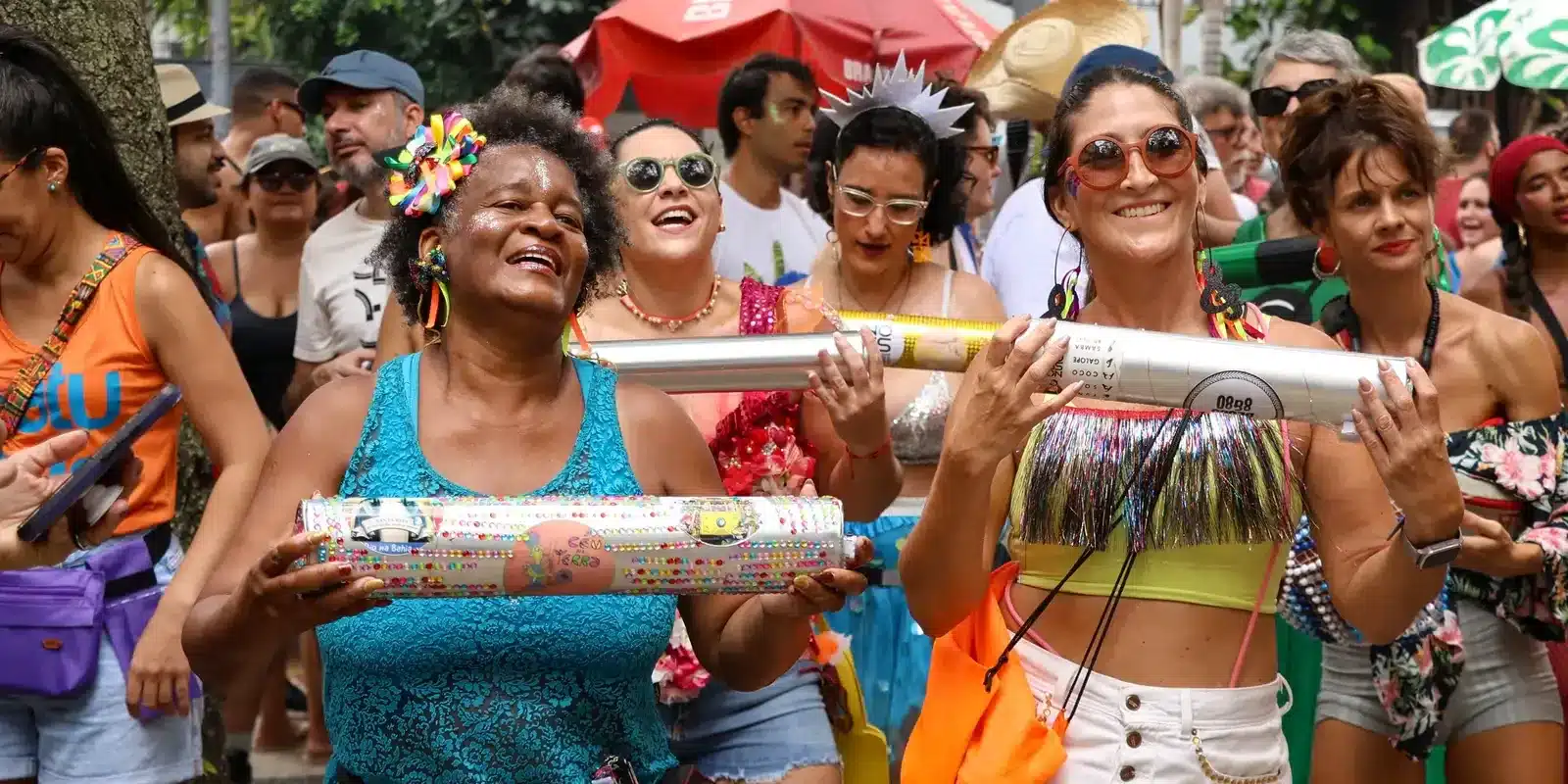 Mulheres sorrindo e celebrando em um bloco de rua, transmitindo alegria e autoaceitação.da autoaceitacao