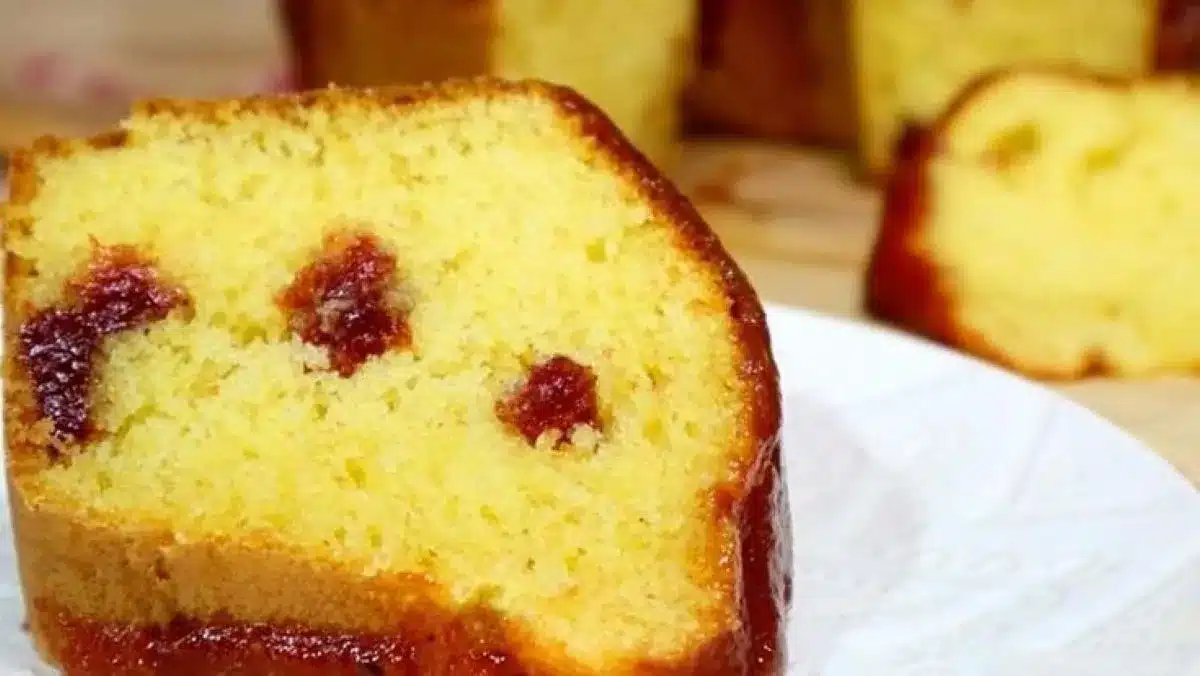 Fatia de bolo de fubá com goiabada, fofinho e dourado, servido em um prato branco.