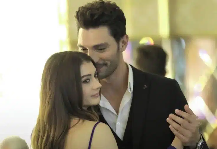 Imagem da série 'Esqueça-me Se Puder', mostrando um casal dançando intimamente, com o homem sorrindo e a mulher olhando para frente, ambos em um momento romântico e elegante.