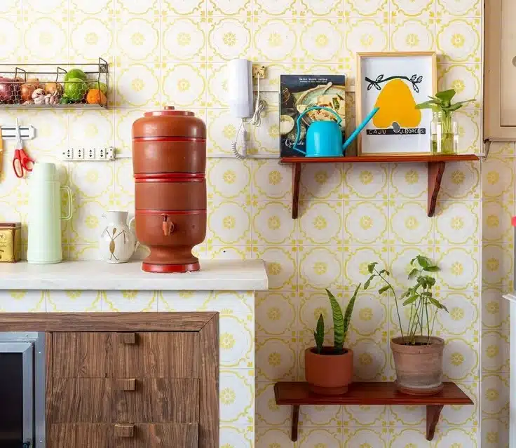 Filtro de barro sobre bancada de cozinha, com elementos decorativos e plantas ao fundo.