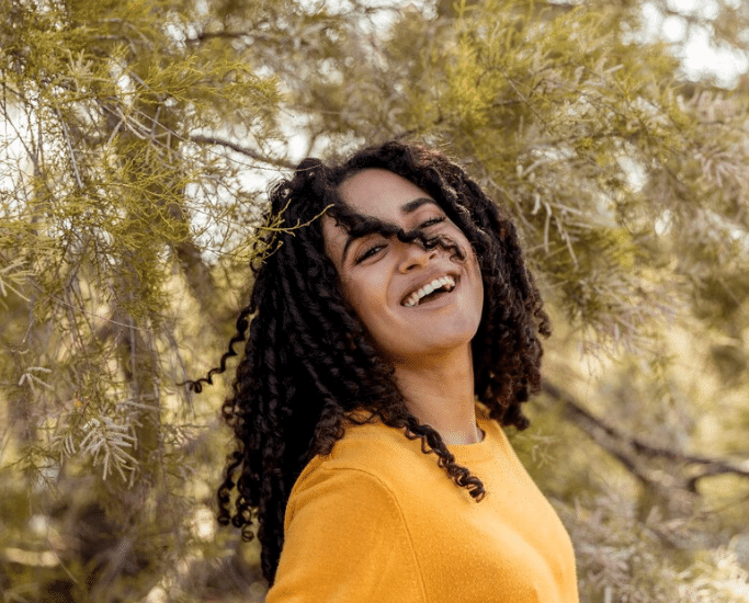 Pessoa sorrindo ao ar livre, transmitindo um espírito aventureiro e livre.