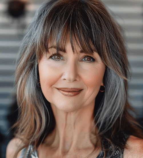 "Mulher com franja desfiada, sorrindo e olhando diretamente para a câmera."