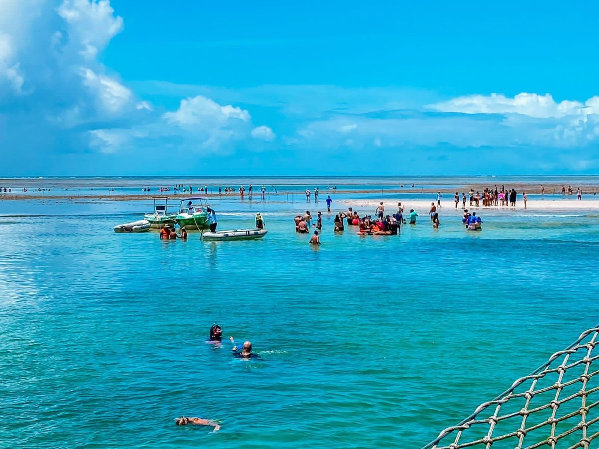 Pessoas aproveitando a beleza natural de Porto Seguro, na Bahia, com águas cristalinas e um cenário paradisíaco.