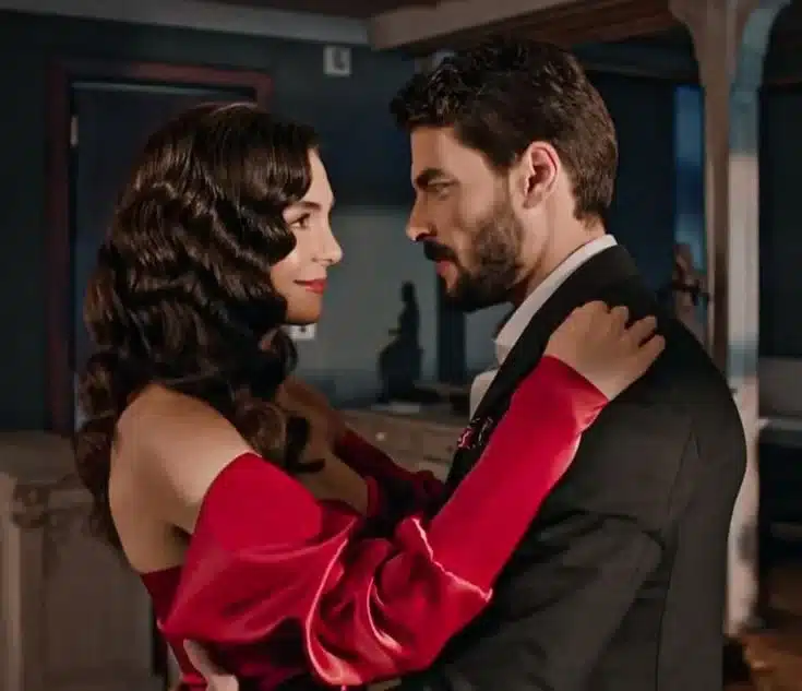 Imagem promocional da série 'Hercai', mostrando um casal em um momento íntimo, com o homem e a mulher olhando nos olhos um do outro, com ela vestindo um vestido vermelho e ele um traje formal.