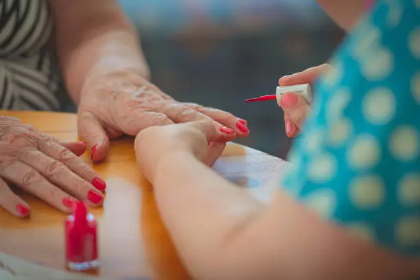 Idosa recebendo manicure, simbolizando os cuidados com as mãos na terceira idade.