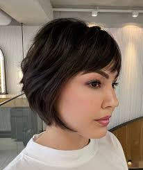 Corte bob desfiado com franja, criando um visual moderno e sofisticado, ideal para mulheres que buscam um estilo leve e cheio de movimento.