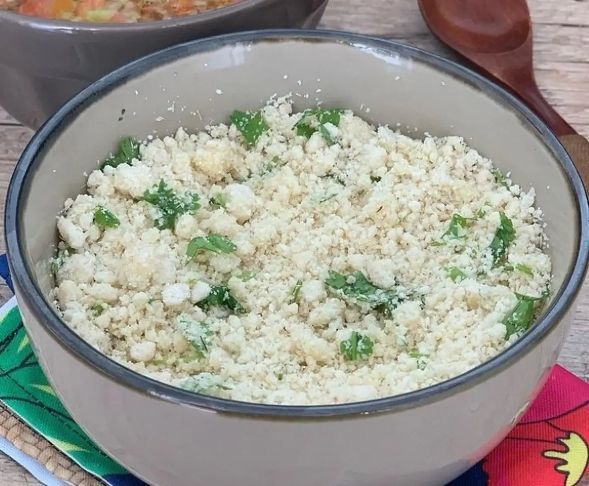 Farofa d'água (jacuba) preparada com farinha de mandioca e temperos frescos como coentro, pronta para ser servida como acompanhamento ou prato principal.