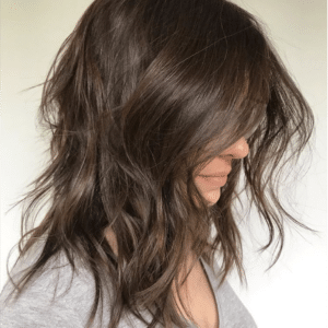 Corte de cabelo bob desfiado longo, com ondas suaves e textura natural, criando um look moderno e descomplicado.