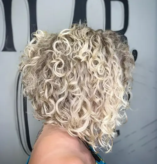  "Mulher com cabelo cacheado em corte long bob, exibindo um estilo moderno e volumoso."