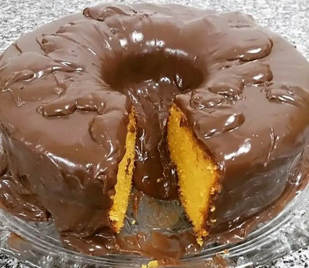 Bolo de cenoura com calda de chocolate crocante, mostrando uma fatia com a textura macia do interior.