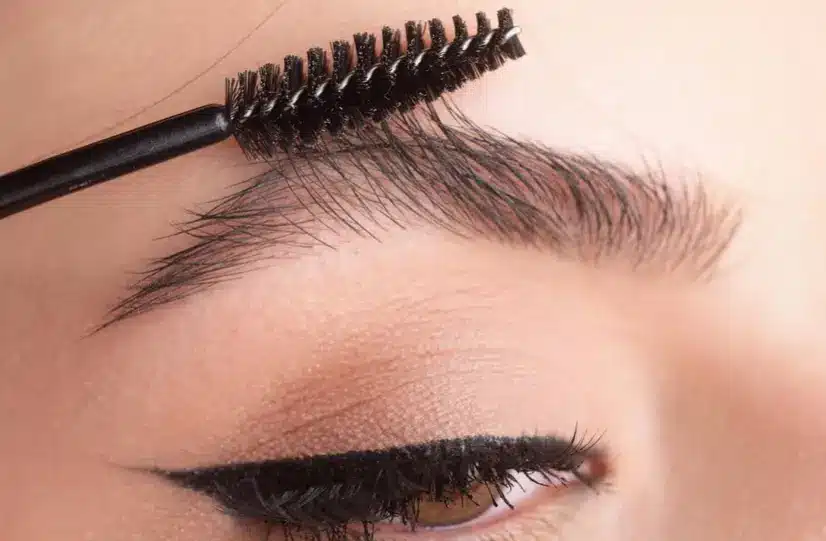 Aplicação de gel de sobrancelhas com escova, contribuindo para o fortalecimento dos fios.