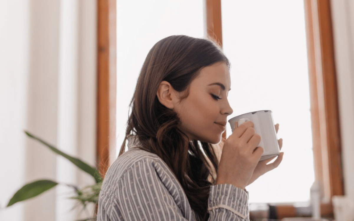 Mulher relaxando e tomando chá, aproveitando os benefícios para a saúde.
