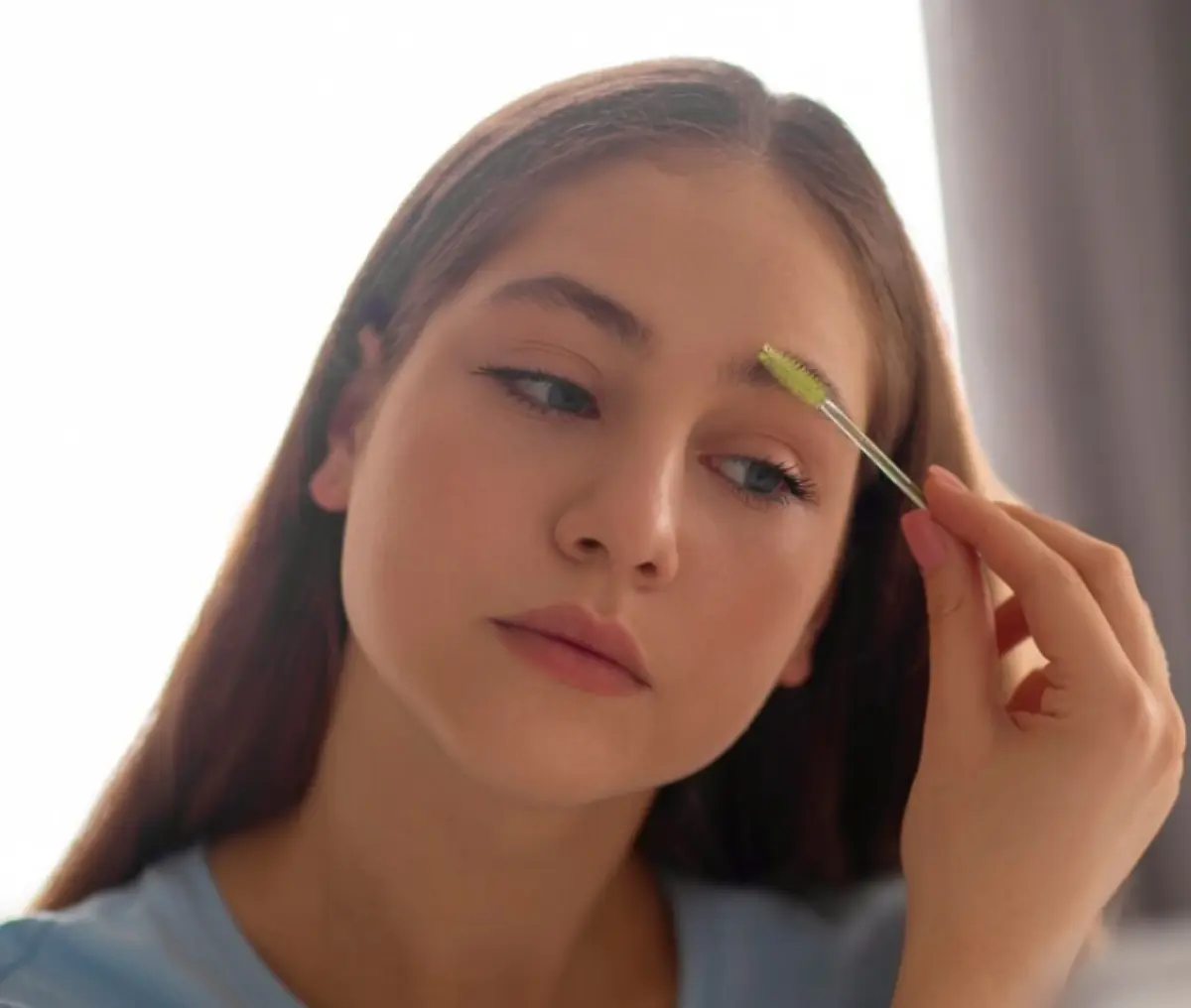 Pessoa aplicando gel para sobrancelhas com escova, promovendo o crescimento e saúde dos fios.