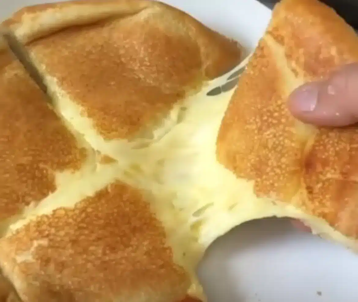Pão de queijo na frigideira sendo puxado, mostrando seu recheio derretido.