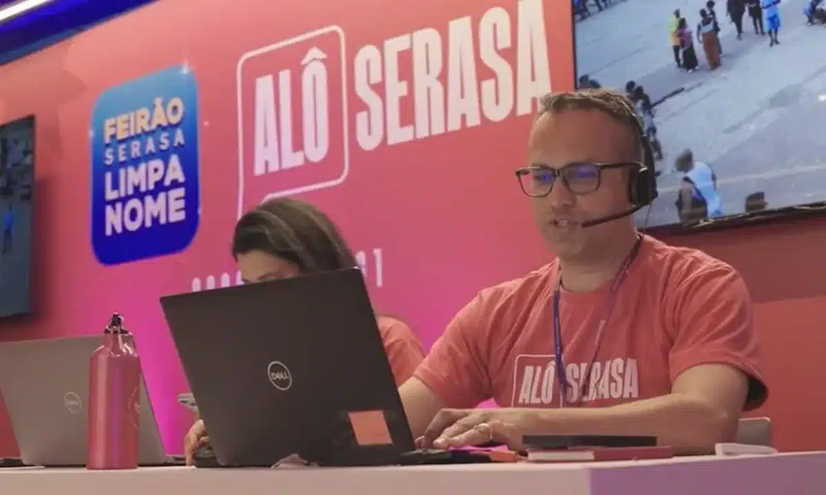 Atendente do 'Alô Serasa' realizando negociações com clientes em um estande de atendimento.