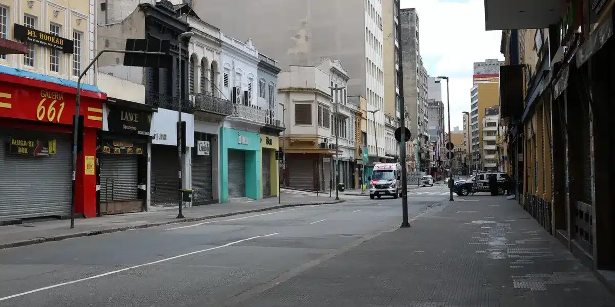 Rua com comércios fechados e pouca movimentação, representando um feriado nacional.