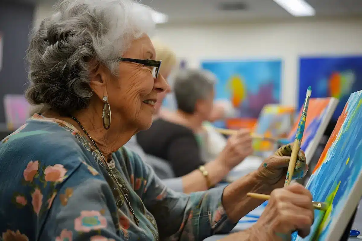 Idosas participando de uma sessão de arteterapia, pintando telas coloridas.