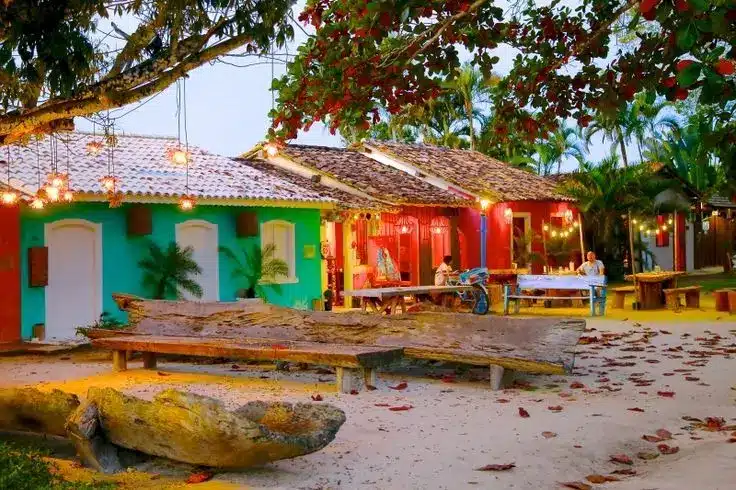A charmosa praia de Trancoso com suas casas coloridas e atmosfera tranquila Casas coloridas e iluminadas em uma praia tranquila de Trancoso, criando um ambiente acolhedor e vibrante.